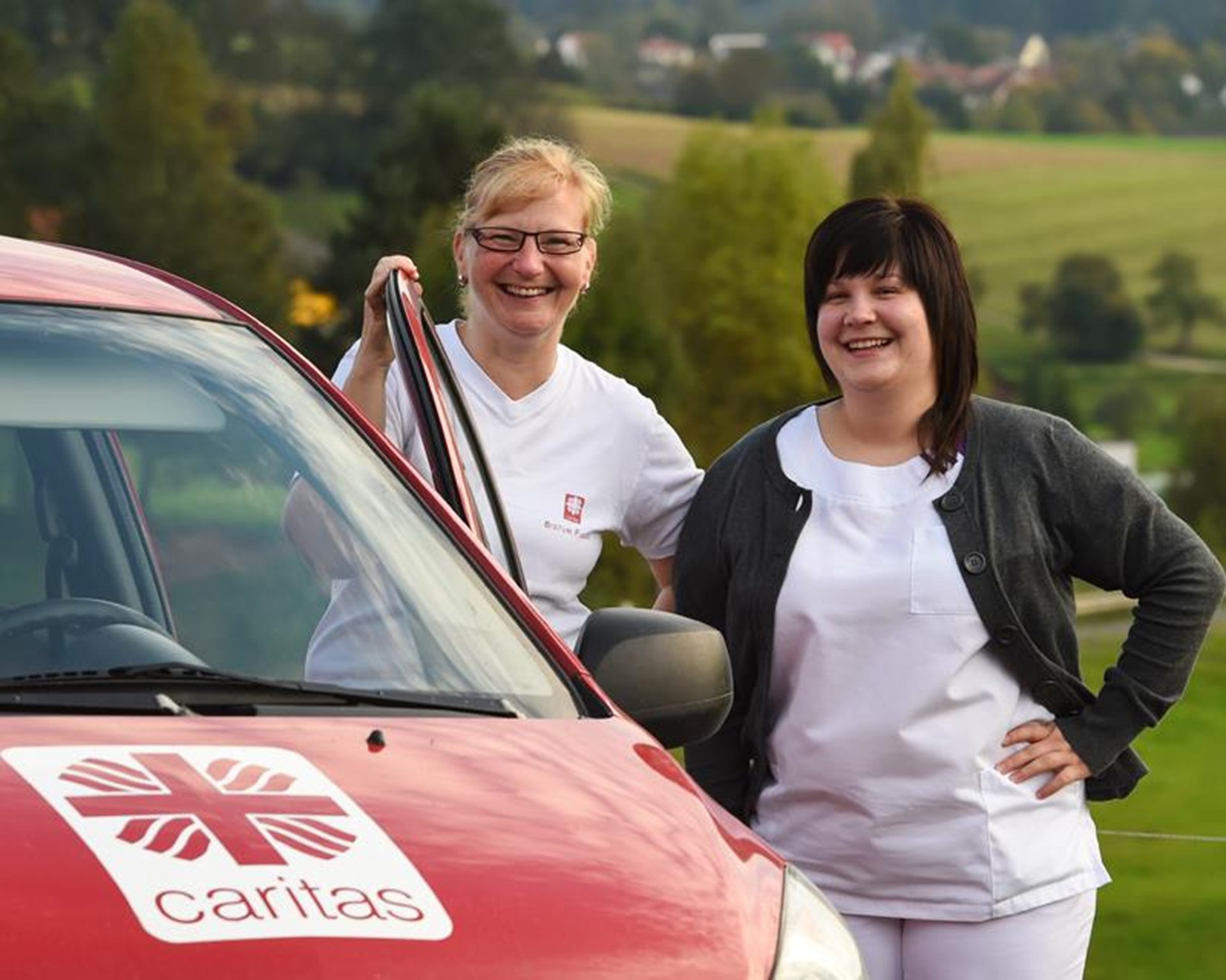 Caritas-Sozialstation - zwei Mitarbeiterinnen vor einem Auto